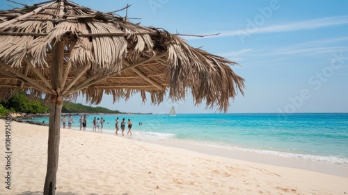 Tropical beach scene with a palm umbrella and clear ocean. photo