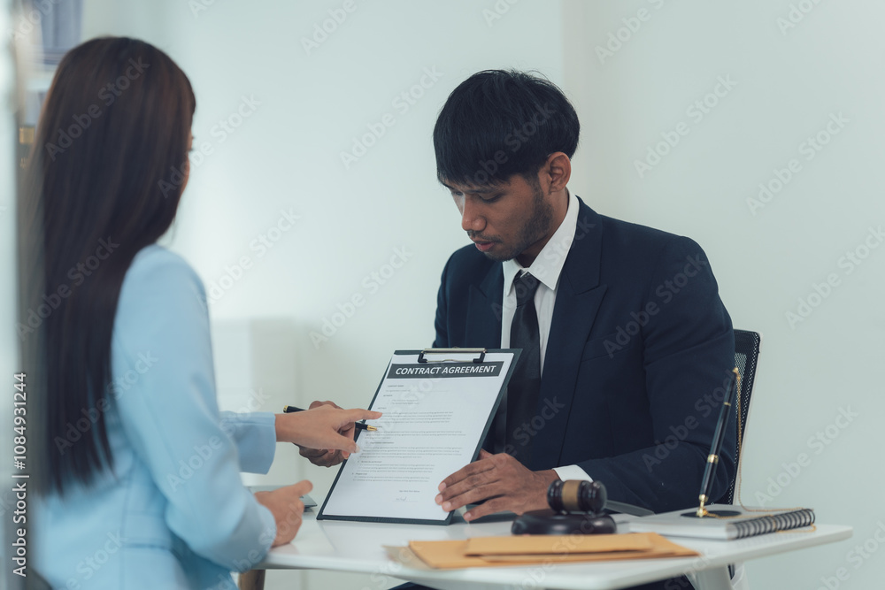 Business Contract Signing: A serious businessman reviews a contract with a client, demonstrating a professional and focused approach in a modern office setting. Business Contract Signing: A serious businessman reviews a contract with a client, demonstrating a professional and focused approach in a modern office setting.