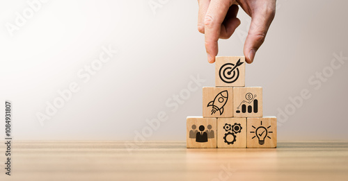 Quadro em tela Hand arranging wooden blocks with business icons symbolizing startup growth, tea