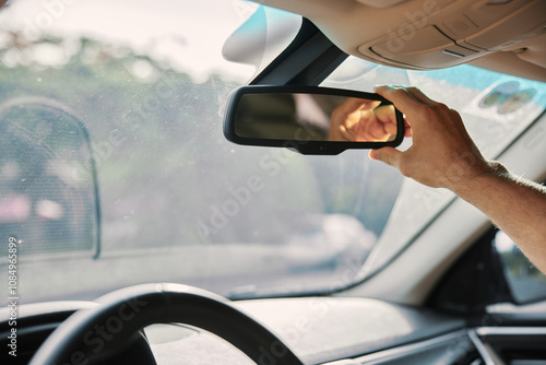 Adjusting a car s rearview mirror while driving in a sunny environment photo