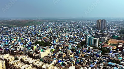 Wide angle drone view descending over dense slums interspersed with buildings in Mumbai's Mankhurd area, showcasing urban density and contrast. Drone view over Mumbais slum photo