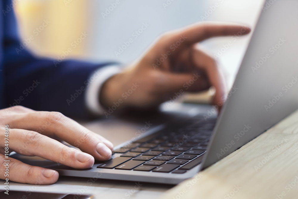 In a close-up shot, male hands are seen typing on the keyboard of a cutting-edge laptop, with an office scene softly blurred in the background. In a close-up shot, male hands are seen typing on the keyboard of a cutting-edge laptop, with an office scene softly blurred in the background.