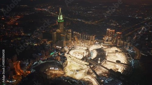 Aerial view at night of the illuminated Grand Mosque and Abraj Al-Bait Clock Tower in Mecca, showcasing the city’s vibrant glow as lights shimmer across the holy site