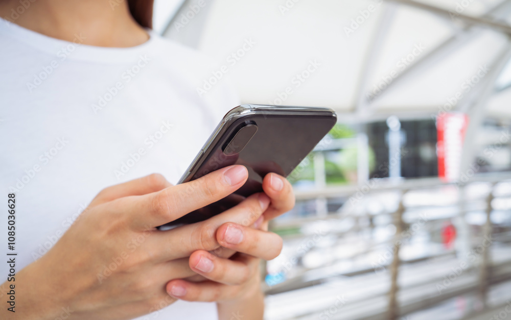 Woman holding smartphone while walking in the urban city. The concept of using the phone is essential in everyday life. Woman holding smartphone while walking in the urban city. The concept of using the phone is essential in everyday life.