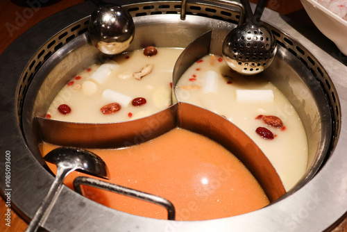 Chinese Hotpot soup divide to three portion with pork bone soup and tomato soup. Large tray and spoon on the side for hot pot photo