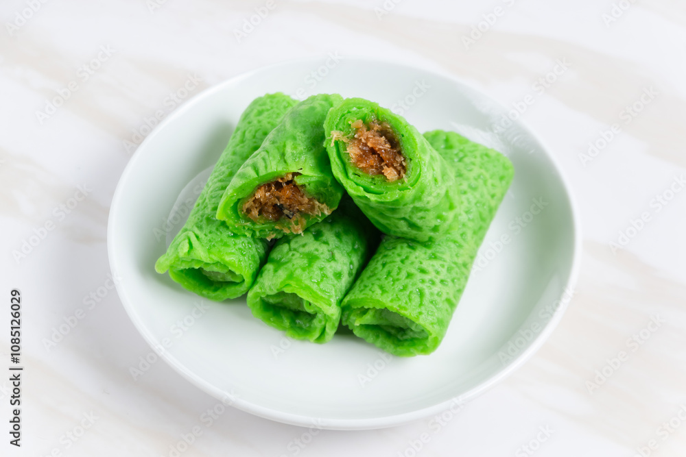 Kue dadar gulung or rolled pancake or sweet coconut pancake, an Indonesian dessert made from wheat flour with grated coconut mixed with palm sugar. Kue dadar gulung or rolled pancake or sweet coconut pancake, an Indonesian dessert made from wheat flour with grated coconut mixed with palm sugar.