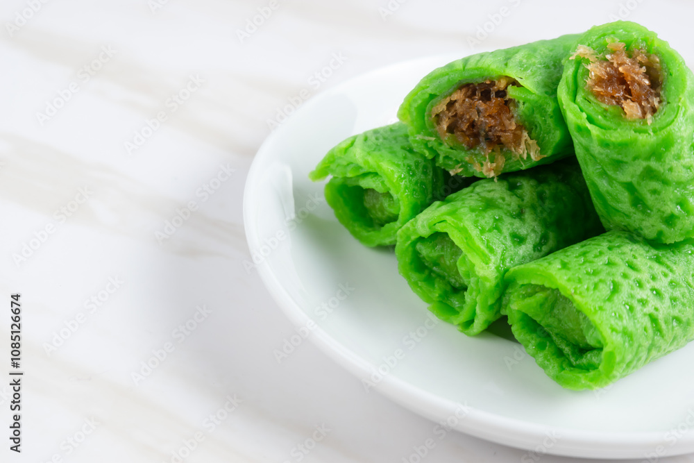 Kue dadar gulung or rolled pancake or sweet coconut pancake, an Indonesian dessert made from wheat flour with grated coconut mixed with palm sugar. Kue dadar gulung or rolled pancake or sweet coconut pancake, an Indonesian dessert made from wheat flour with grated coconut mixed with palm sugar.