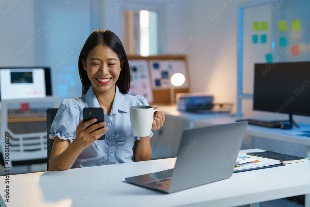 Asian woman, businesswoman sitting texting FaceTime or watching video on her smartphone while holding a cup of coffee drinking relaxing while working at home office. Work lifestyle concept. Asian woman, businesswoman sitting texting FaceTime or watching video on her smartphone while holding a cup of coffee drinking relaxing while working at home office. Work lifestyle concept.