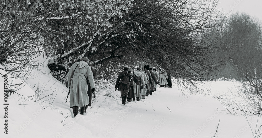 Men Dressed As White Guard Soldiers Of Imperial Russian Army In Russian Civil War s Marching Through Snowy Winter Forest. Army on Marching. Historical Reenactment of Civil War. Black And White