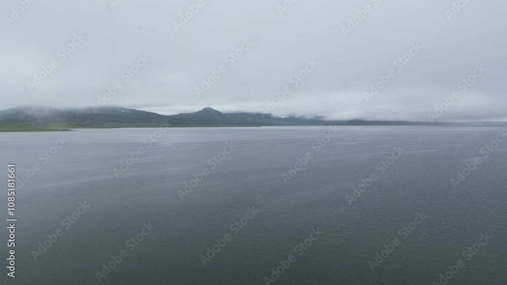 A serene view of a calm and peaceful lake gently surrounded by majestic mountains underneath a cloudy sky A serene view of a calm and peaceful lake gently surrounded by majestic mountains underneath a cloudy sky