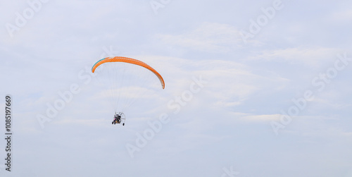 A Motorized Paragliding machine is flying midair against the Skyscape, is a popular Recreational sport in Indian subcontinent..