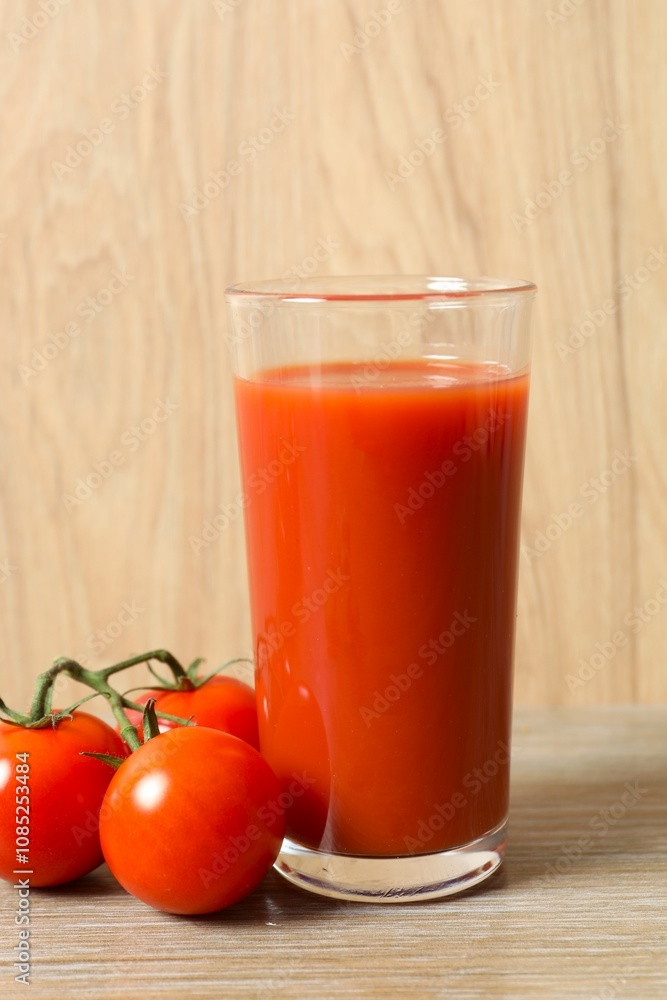 Tomato juice in a glass and fresh tomatoes on the table Tomato juice in a glass and fresh tomatoes on the table