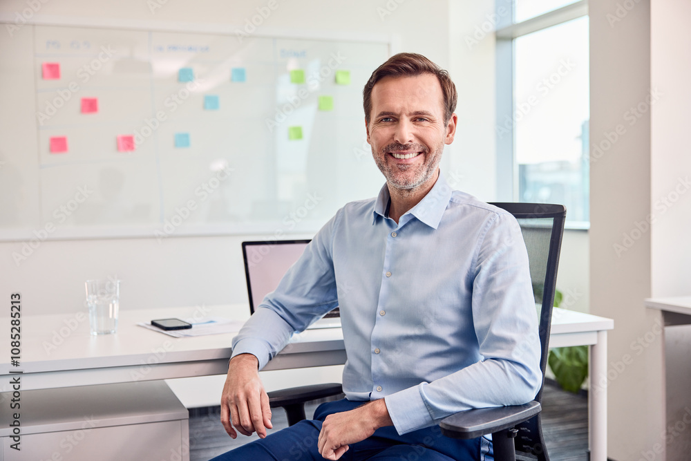 Obraz premium Portrait of smiling businessman sitting at office looking at camera