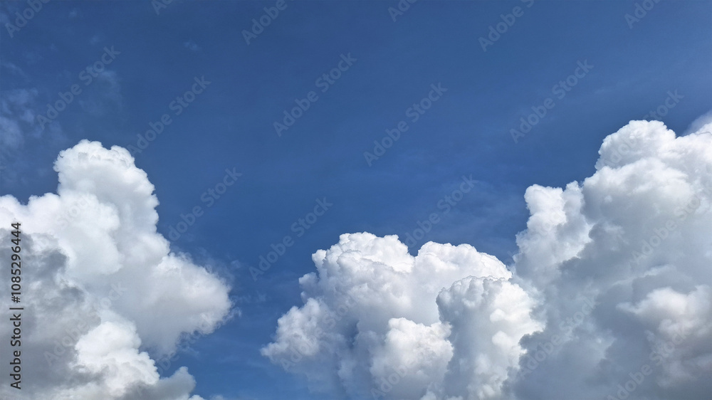 Clear blue sky with fluffy white clouds. The clouds look like scattered cotton, creating a peaceful and calm scenery with Blue sky background. Clear blue sky with fluffy white clouds. The clouds look like scattered cotton, creating a peaceful and calm scenery with Blue sky background.