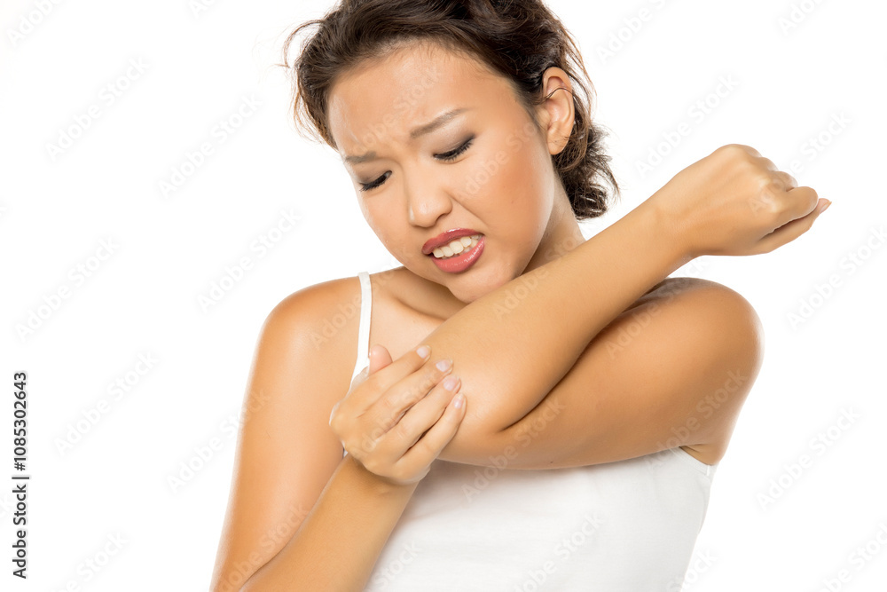 Asian woman with pain in the elbow, holding it with arm with painful expression on her face Asian woman with pain in the elbow, holding it with arm with painful expression on her face