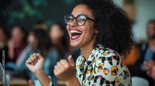 A young woman with glasses and a vibrant patterned shirt laughs with unrestrained joy, celebrating a personal triumph. Her infectious happiness is contagious.