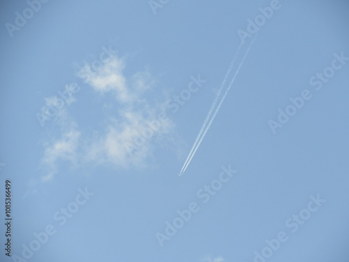 Clear blue sky with a single airplane contrail, symbolizing freedom and open air space.