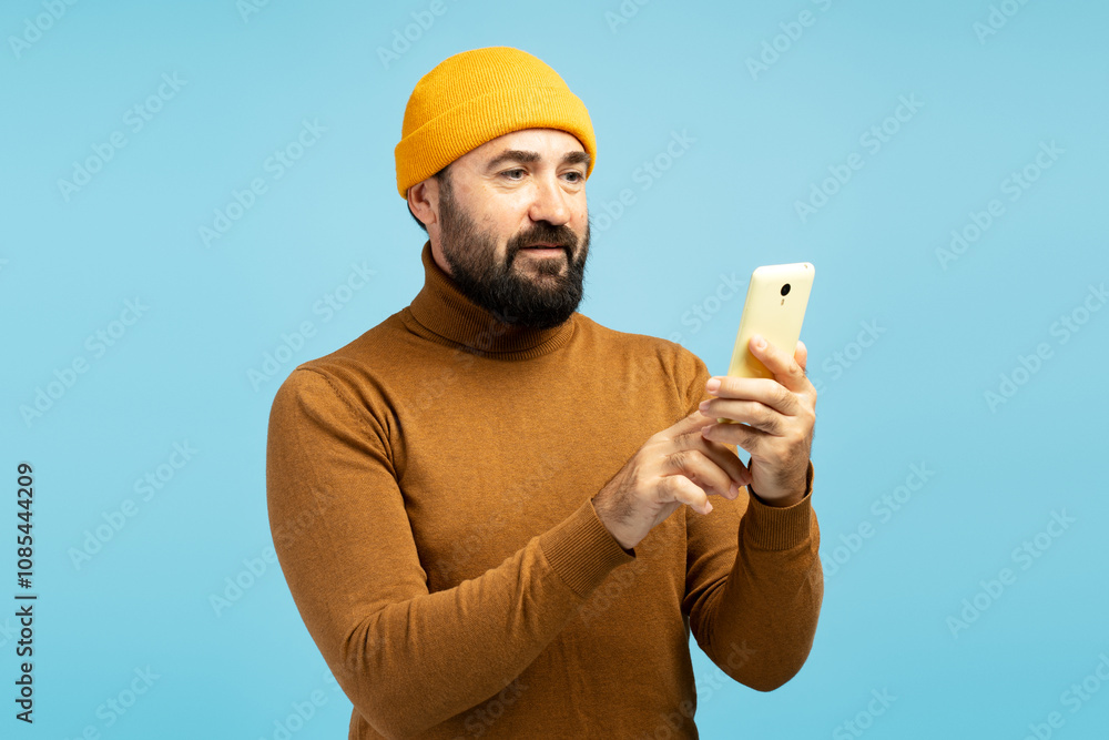Bearded man using smartphone on blue background, modern man browsing internet on mobile phone Bearded man using smartphone on blue background, modern man browsing internet on mobile phone