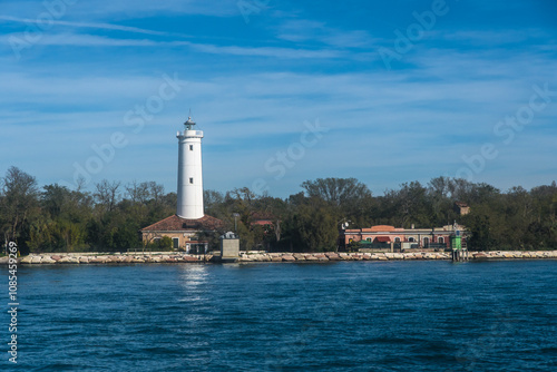 Il faro Rocchetta, sull’estremità ovest dell’isola del Lido di Venezia si riflette nell’acqua della laguna in una giornata autunnale photo