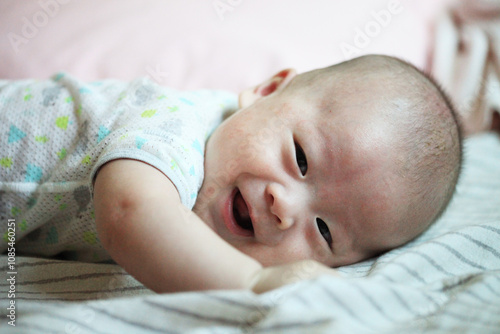 Happy baby laying on a soft blanket in a cozy room, enjoying playful moments, capturing joy and innocence in a serene environment