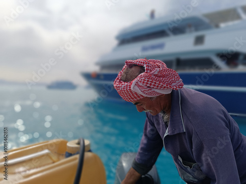 Old Sailor in the Sea Riding and Sailing with his Boat An old sailor with a white with a white mustache who is wearing a Bedouin Scarf on his head