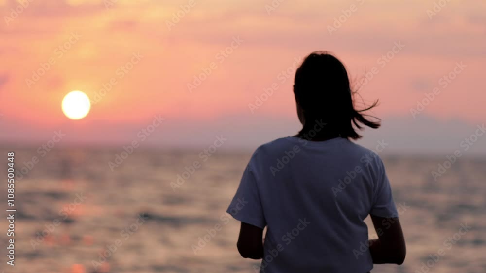 A silhouette of a woman stands by the sea, admiring the sunset while throwing stones into the water. This video captures a peaceful moment of reflection and connection with nature A silhouette of a woman stands by the sea, admiring the sunset while throwing stones into the water. This video captures a peaceful moment of reflection and connection with nature