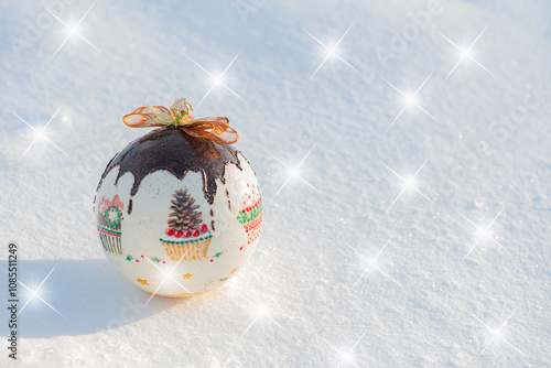 Christmas card. Christmas bauble lying on natural snow on a frosty sunny day, with decorative stars.