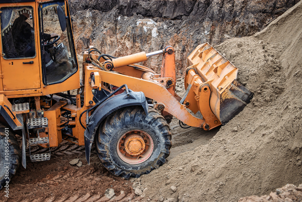 Obraz premium A powerful orange excavator skillfully scoops sand on a construction site during a sunny afternoon, showcasing its strength and efficiency