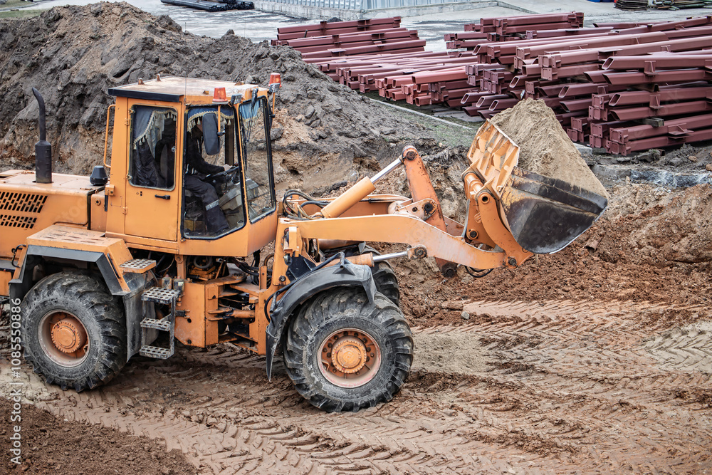 Construction site activity showcasing a yellow loader excavating dirt on a busy workday amidst stacked materials in the background Construction site activity showcasing a yellow loader excavating dirt on a busy workday amidst stacked materials in the background