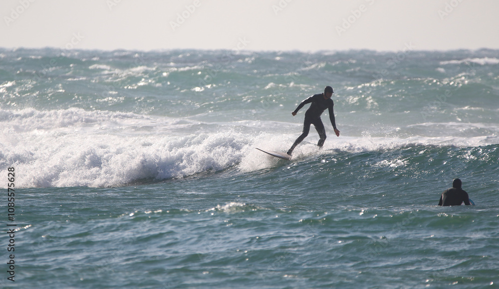 surfer in a wetsuit on a board glides through the waves in a strong wind