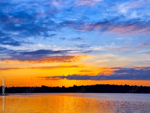 vivid colorful color of sunset with clouds.Sunset with mountain above lake reflection in water.