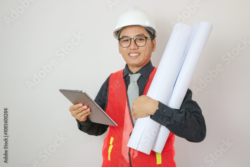 Young Asian civil engineer or construction supervisor wearing a helmet looks away and smiles while inspecting a construction site. photo