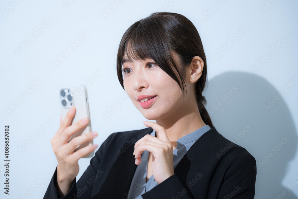 Business scene of young woman in suit making a phone call Tap closeup on light blue background Business scene of young woman in suit making a phone call Tap closeup on light blue background