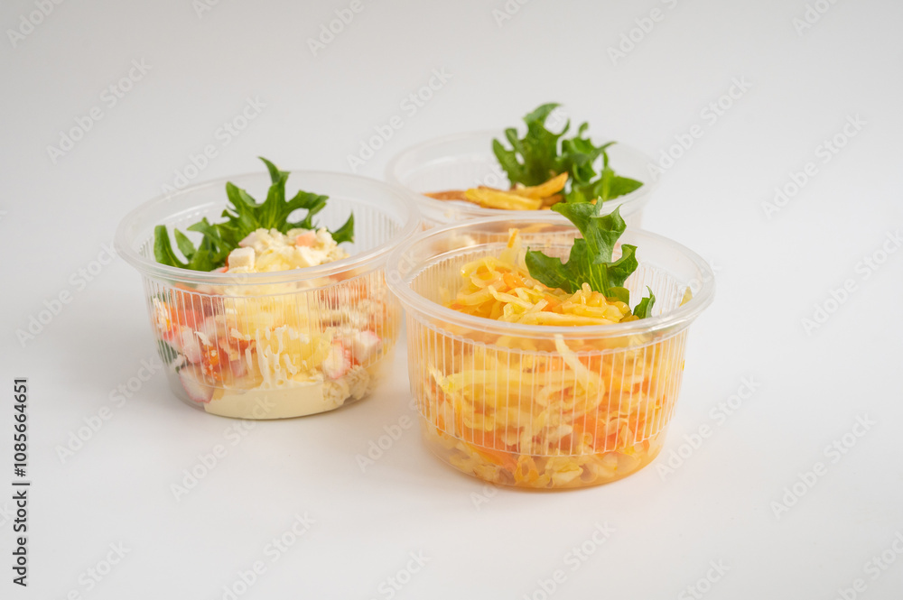 Three clear plastic containers with different salads and fries, garnished with fresh greens. Three clear plastic containers with different salads and fries, garnished with fresh greens.