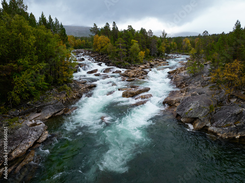 A Serene River Flowing Gently Through an Autumn Forest Landscape Full of Colorful Leaves photo