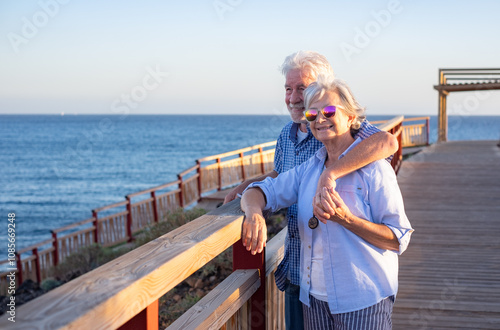 Tableau sur toile Handsome relaxed senior couple of retirees hugging face the sea enjoying vacation and free time at sunset