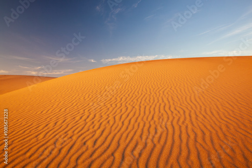 Sand dune at sunset, bright orange with wind ripples