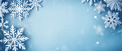 Snowflakes of different sizes and shapes creating a winter frame on a light blue background with a brighter central area. Christmas template.