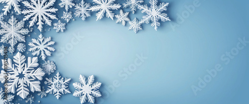 Snowflakes of different sizes and shapes creating a winter frame on a light blue background with a brighter central area. Christmas template.