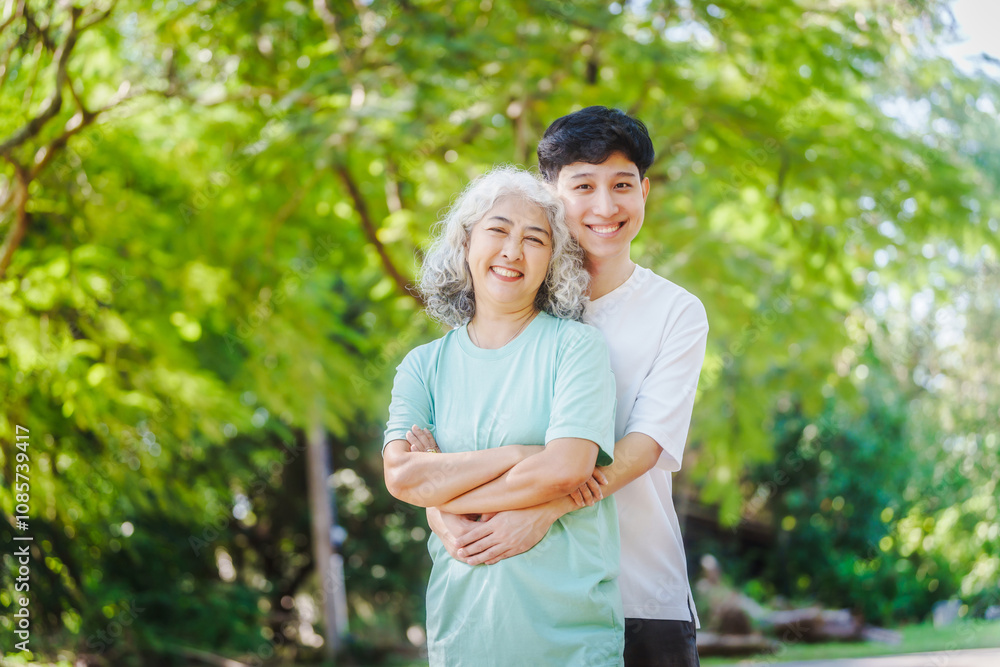 Young son and his mature mom asian people share loving hug in beautiful park, surrounded by nature. Their happiness radiates as they bond outdoors, celebrating family love and togetherness. Young son and his mature mom asian people share loving hug in beautiful park, surrounded by nature. Their happiness radiates as they bond outdoors, celebrating family love and togetherness.