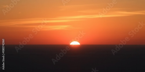 Vibrant orange and pink hues illuminate the sky as the sun rises over the calm ocean, sunrise, sky, beauty