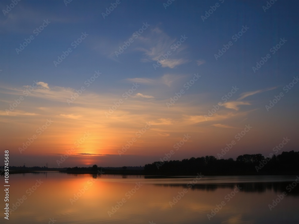 Vibrant sunrise over a calm lake with silhouetted trees in the foreground, reflection, silhouette, sky Vibrant sunrise over a calm lake with silhouetted trees in the foreground, reflection, silhouette, sky