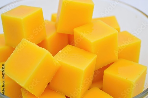 Close-up of vibrant orange mango cubes in a glass bowl capturing freshness and tropical delight.