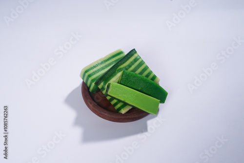 Sticky layer cake or Kue Lapis on wooden plate isolated on white background. Indonesian traditional dessert made from rice flour and coconut milk, steamed layer by layer served on banana leaves. Selec photo