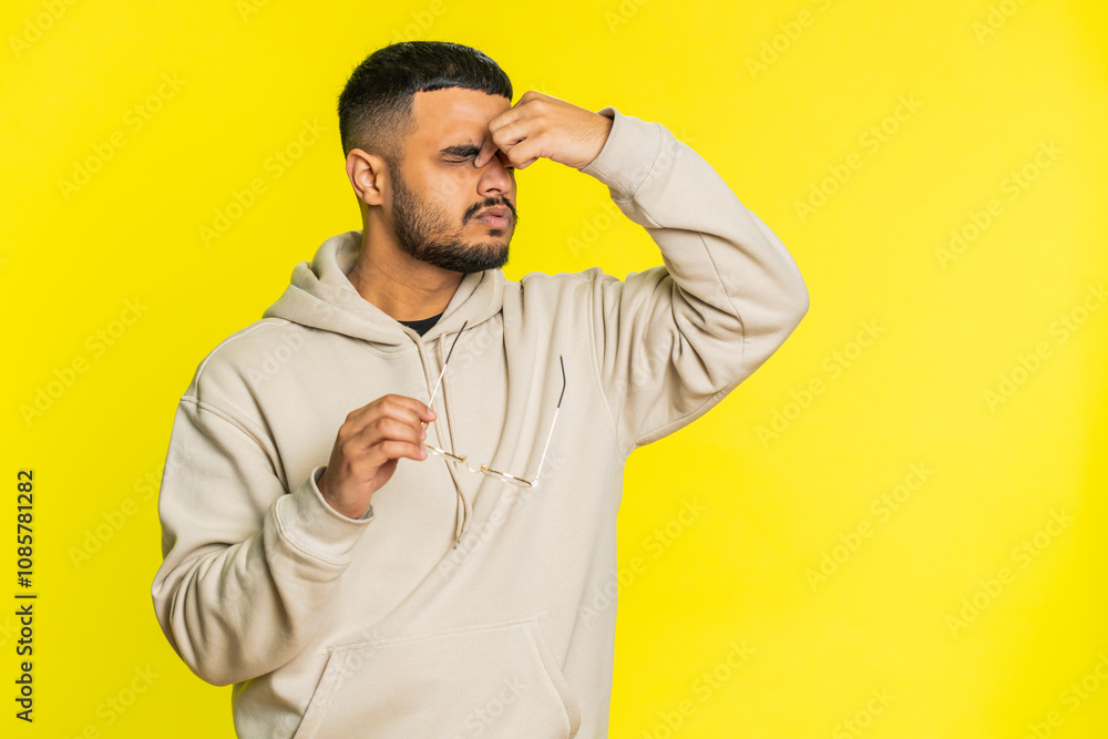 Exhausted tired Indian young man takes off glasses, feels eyes pain, being overwork burnout from long hours working. Sleepy exhausted Arabian guy rubbing eyes isolated on studio yellow background Exhausted tired Indian young man takes off glasses, feels eyes pain, being overwork burnout from long hours working. Sleepy exhausted Arabian guy rubbing eyes isolated on studio yellow background