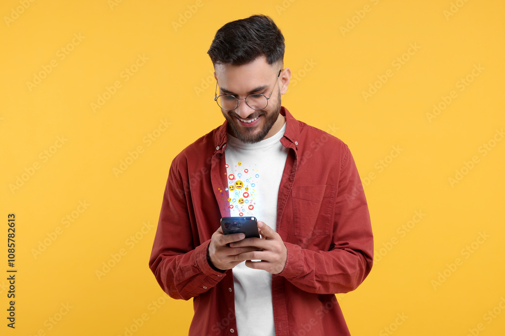 Happy man using mobile phone on orange background. Different notification signs over gadget Happy man using mobile phone on orange background. Different notification signs over gadget