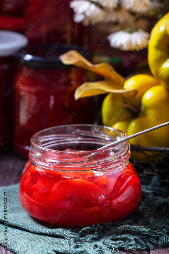 Quince jam in a glass jar, quince in a basket and a bouquet of chrysanthemums. Autumn still life.