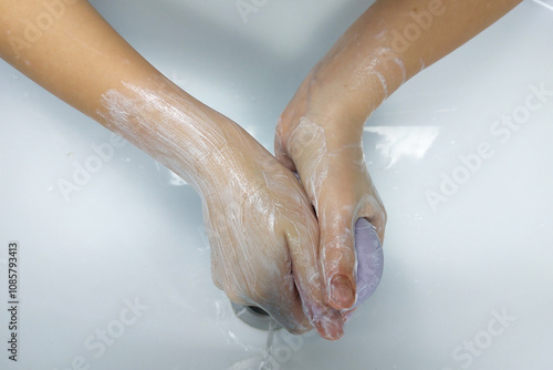 Children's hands with soap under running water in the sink. Clean hands after washing.