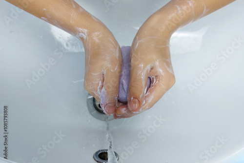 Children's hands with soap under running water in the sink. Clean hands after washing.