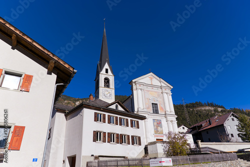 Looking up to church surrounded by houses at Swiss mountain village of Alvaneu on a sunny autumn day. Photo taken November 15th, 2024, Alvaneu, Switzerland. photo